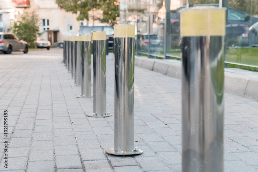 Fototapeta premium Polished Silver Bollards Line a Paved Pathway in Urban Setting