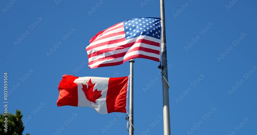 Canadian and American flags wave side by side at the country border ...