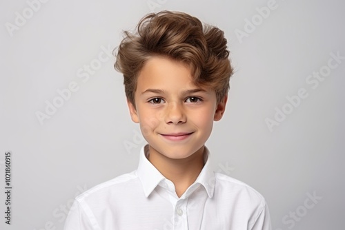 Portrait of a cute little boy in a white shirt on a gray background