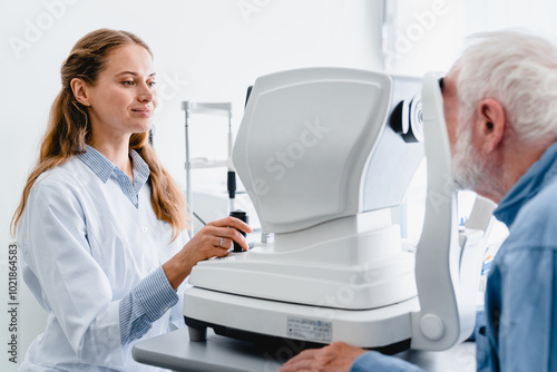 Quadro su tela Young female oculist checking senior male patient`s vision using special equipme