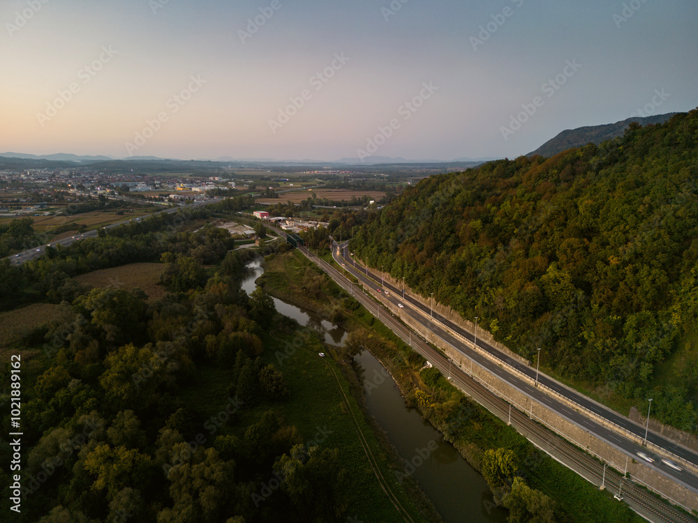Aerial view of Sava river at sunset, with cars and trucks passing next to the embankment Aerial view of Sava river at sunset, with cars and trucks passing next to the embankment