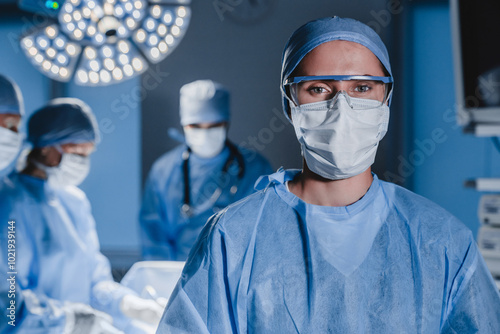 Portrait of young female surgeon doctor surrounded by her team. Group of surgeon in operation theatre. photo