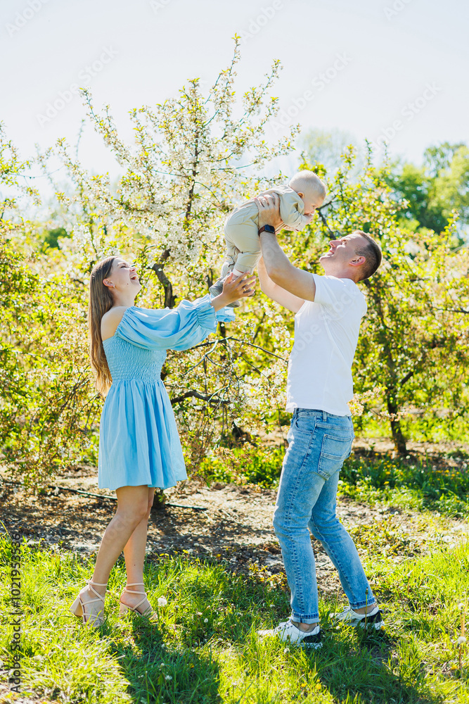 Fototapeta premium A young married couple, a man, a woman and a little son, are walking in the park. Time for a walk, mom, dad and small child.
