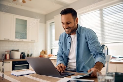 Happy man using laptop while working at home.