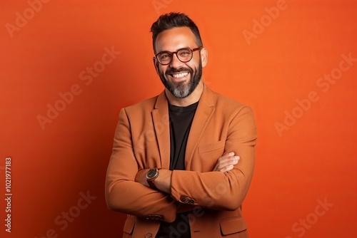 Portrait of a handsome bearded Indian man with glasses against orange background photo