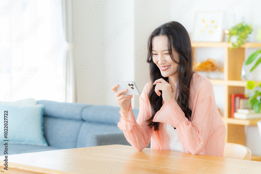 部屋でスマホを操作する女性 部屋でスマホを操作する女性
