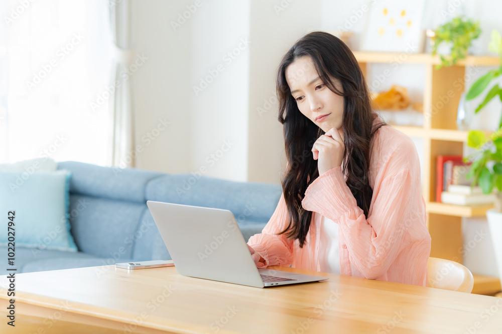 自宅でノートパソコンを操作する女性 自宅でノートパソコンを操作する女性