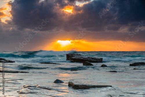 Moody sunrise seascape with clouds and sunrays at the rocky inlet photo