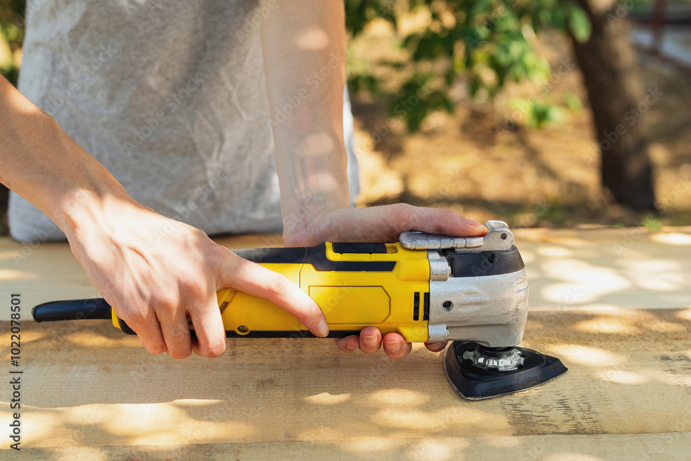 Craftswoman Is Sanding A Wooden Plank Using An Electric Sander Outdoors Craftswoman Is Sanding A Wooden Plank Using An Electric Sander Outdoors