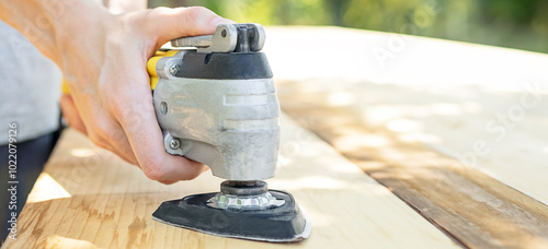 Tablou pe pânză Carpenter Using Oscillating Multi Tool For Sanding Wood Plank Outdoors