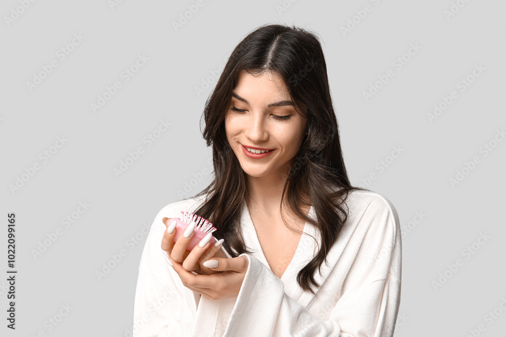 Beautiful young woman with pink hair brush on grey background Beautiful young woman with pink hair brush on grey background