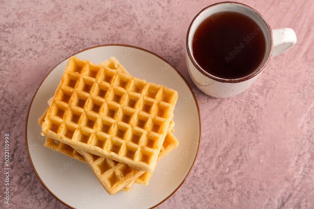 Plate with delicious Belgian waffles and cup of tea on pink background Plate with delicious Belgian waffles and cup of tea on pink background