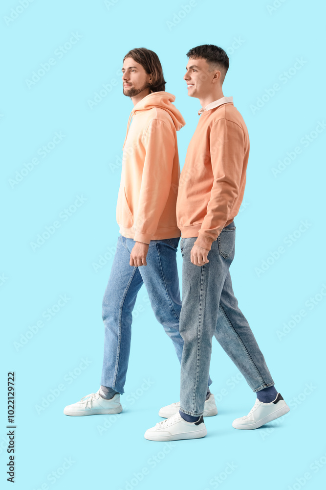 Young men in white sneakers walking on blue background Young men in white sneakers walking on blue background