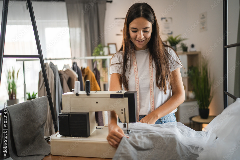 Adult woman tailor or fashion designer stand and work on sewing machine Adult woman tailor or fashion designer stand and work on sewing machine