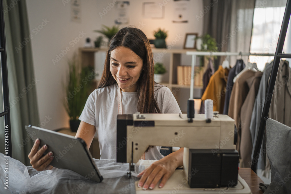 Adult woman use tablet near sewing machine in home workspace Adult woman use tablet near sewing machine in home workspace