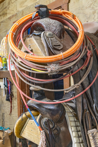 Old saddles and lariats, or lassos, on a rack.