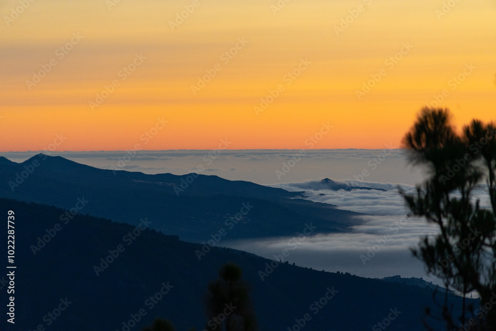 Obraz premium Stunning sunset view over mountain range with clouds filling the valley in serene evening light