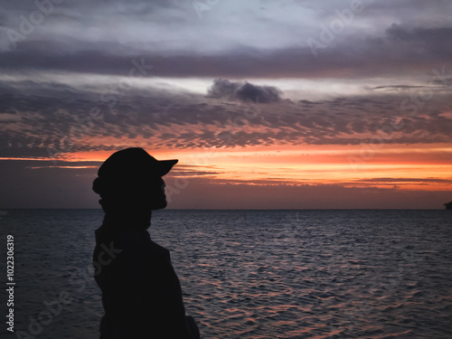 Silhouette photo of a woman wearing a hijab enjoying the sunset on the beach