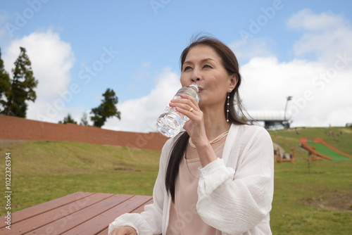 琵琶湖バレイで水分補給をするシニア女性