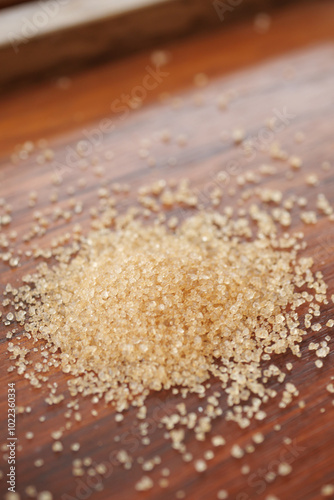 This image features a closeup view of a pile of brown sugar resting on a wooden surface