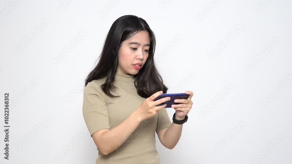 Beautiful Asian Woman playing mobile game on smartphone while standing Isolated On White Background Beautiful Asian Woman playing mobile game on smartphone while standing Isolated On White Background