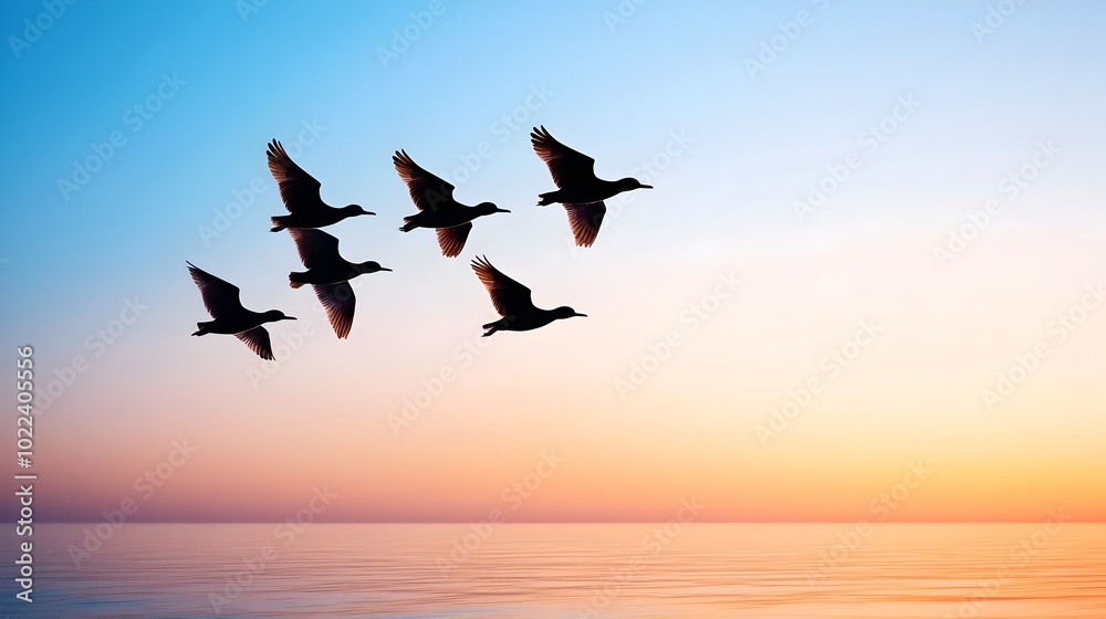 Fototapeta premium Flock of birds silhouetted against a beautiful golden hued sunset sky their graceful movements creating a sense of peaceful tranquility and wanderlust