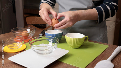 Process of making dough. Woman separates egg white from yolk in kitchen. Scales and eggs, utensils on wooden table. Baking macarons at home. Hands in close-up.