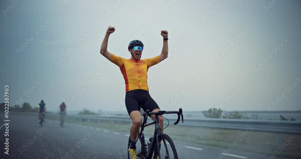 Leading Rider Lifts His Arms in the Air, Cheering as He Reaches His Goal, His Racing Bike Rolling Steadily Beneath Him. Moment of Achievement Captures His Unstoppable Determination and Endurance
