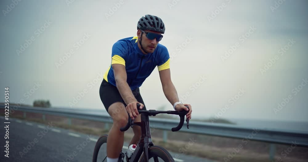 Portrait of a Cyclist Wearing Shorts, Jersey, Helmet and Glasses, Pedaling Steadily on a Quiet Country Road. Focused and Driven, He Pushes Himself Forward, Dedicated to His Endurance Training Portrait of a Cyclist Wearing Shorts, Jersey, Helmet and Glasses, Pedaling Steadily on a Quiet Country Road. Focused and Driven, He Pushes Himself Forward, Dedicated to His Endurance Training