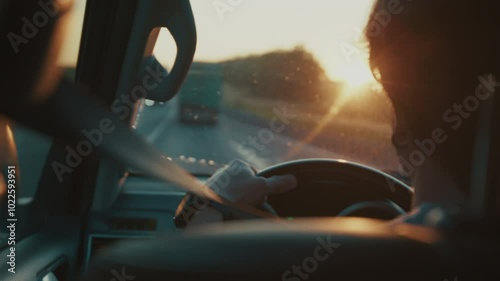 Young man steers the car in heavy traffic on the highway full of trucks