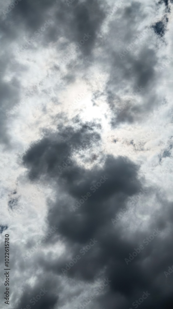 A cloudy sky with varying shades of gray and hints of sunlight peeking through.