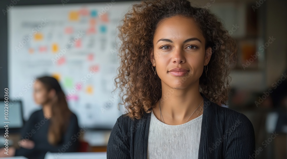 Confident female marketing leader stands in front of an office whiteboard with colorful charts and graphs, she is wearing business casual attire and has curly hair. Confident female marketing leader stands in front of an office whiteboard with colorful charts and graphs, she is wearing business casual attire and has curly hair.