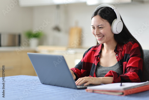 Happy asian student e-learning in the kitchen