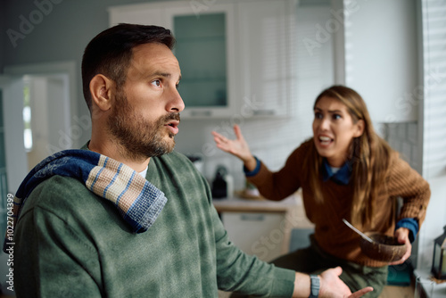 Obraz na plátně Frustrated man arguing with his wife while doing dishes in kitchen