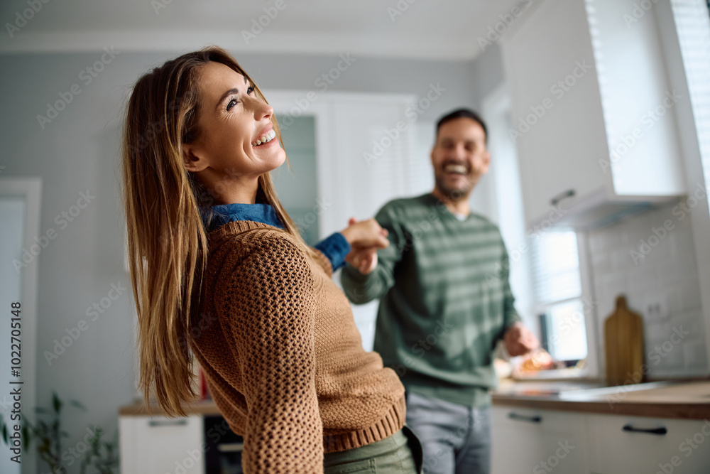 Carefree woman dancing with her husband in kitchen. Carefree woman dancing with her husband in kitchen.