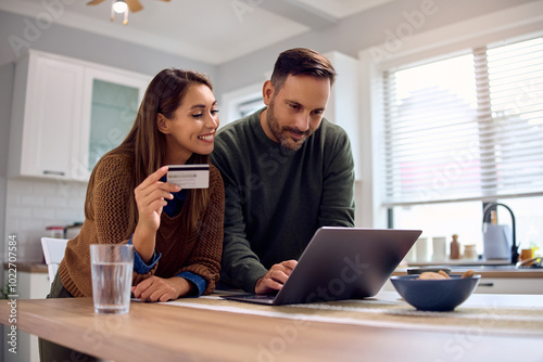 Happy couple using laptop and credit card while ordering online.