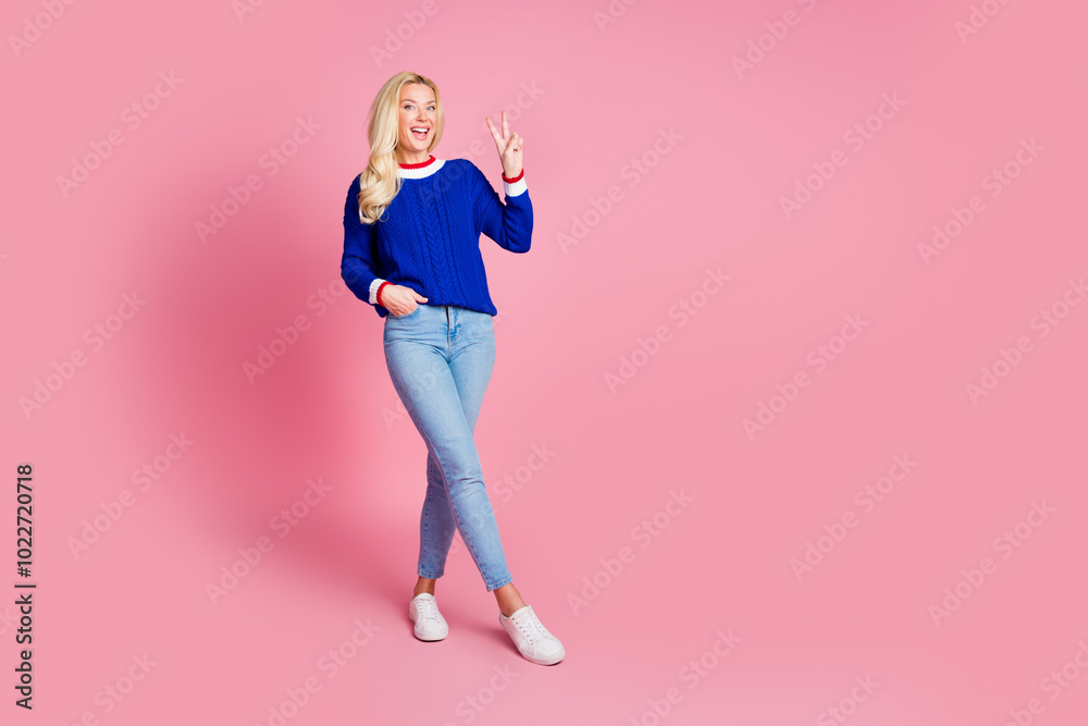 Full size photo of pretty lady demonstrate v-sign empty space wear blue sweater isolated on pink color background Full size photo of pretty lady demonstrate v-sign empty space wear blue sweater isolated on pink color background