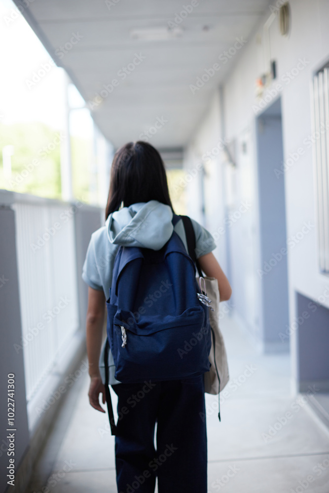 Obraz premium 秋の朝のマンションの廊下で歩いて登校する中学生の姿