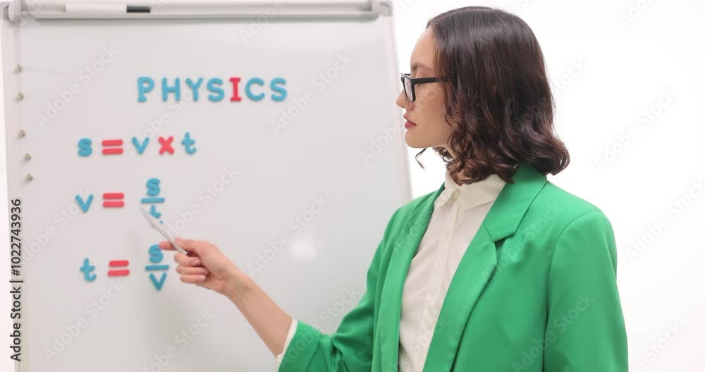 Woman physics teacher explains formula for calculating mass on white background. Pedagogue stands by whiteboard and explains formulas at lesson Woman physics teacher explains formula for calculating mass on white background. Pedagogue stands by whiteboard and explains formulas at lesson