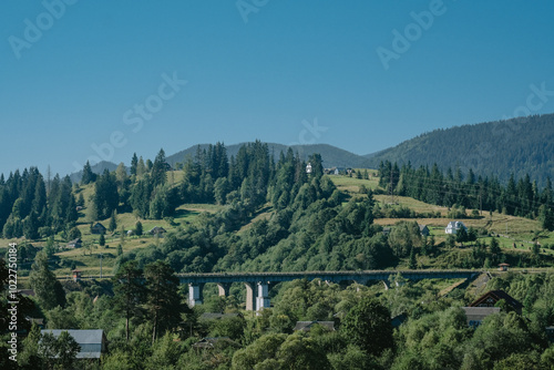 A serene landscape showcasing lush green hills and a bridge surrounded by trees on a clear day in the countryside