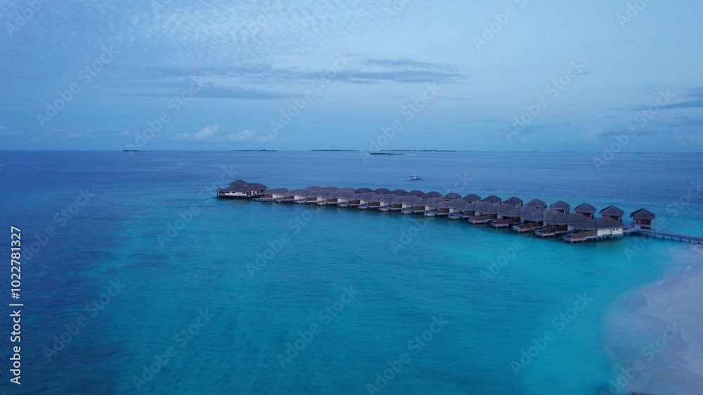 Top view of the sunset over an island in the ocean. Large dark clouds with a pink tinge. Turquoise ocean water, white sand of the beach. Green palm trees and trees. Maldives. Water is like a mirror Top view of the sunset over an island in the ocean. Large dark clouds with a pink tinge. Turquoise ocean water, white sand of the beach. Green palm trees and trees. Maldives. Water is like a mirror