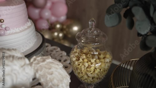 Wallpaper Mural Glass jar of popcorn displayed next to a white and pink cake with balloons in the background Torontodigital.ca