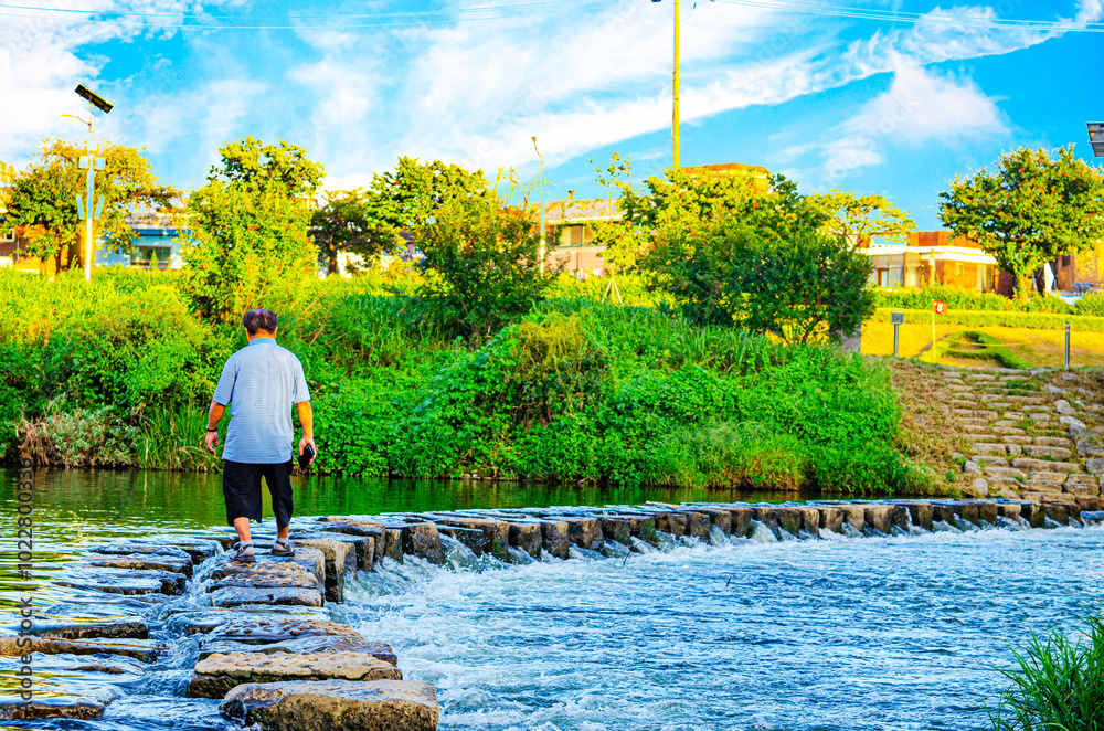 Obraz premium Man walking on stone bridge for across the river