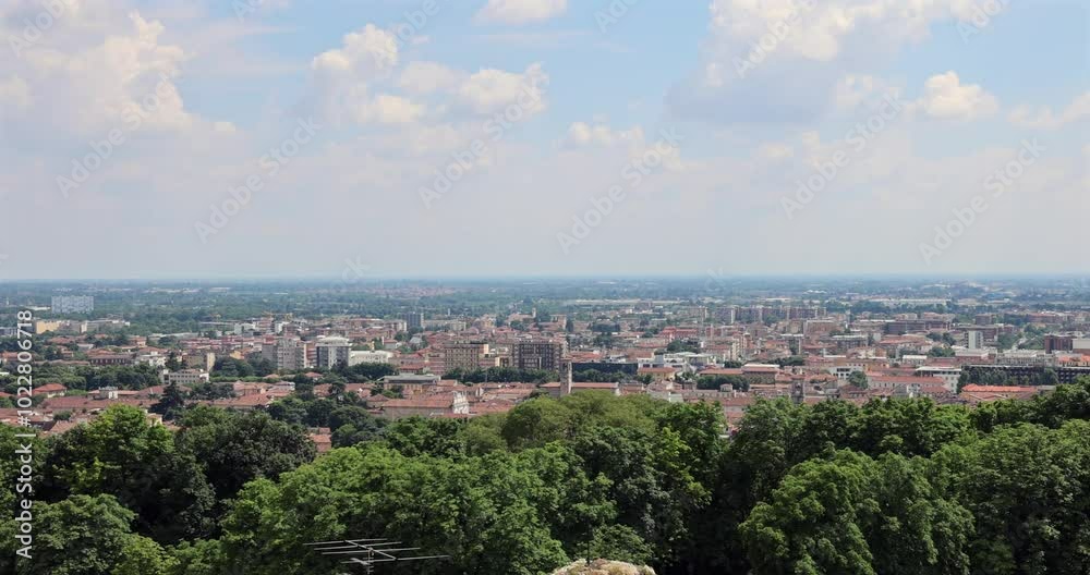 Camera pans left to right over Brescia cityscape, capturing the Duomo dome, modern skyscrapers, and surrounding trees Camera pans left to right over Brescia cityscape, capturing the Duomo dome, modern skyscrapers, and surrounding trees