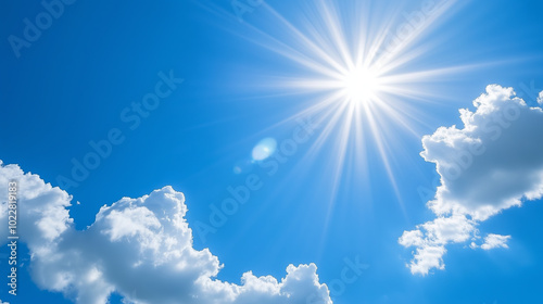 Bright sun shining through puffy white clouds on a clear blue sky.