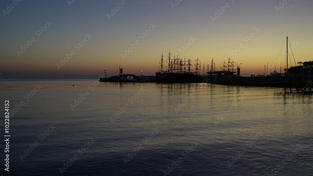 Sunrise at Kemer yacht marina in Antalya, Turkiye. The calm sea reflects the orange sky, capturing the serene beauty of this popular summer vacation spot. Sunrise at Kemer yacht marina in Antalya, Turkiye. The calm sea reflects the orange sky, capturing the serene beauty of this popular summer vacation spot.