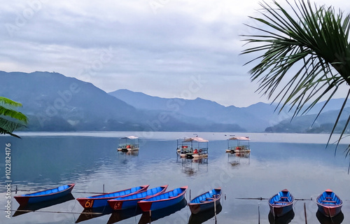 Blue canoes and paddle boats on Phewa lake with distant Mountain ranges photo