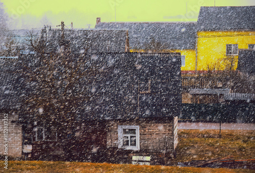 Snow falling heavily in a quaint village on a desolate winter day with a cold and gloomy atmosphere