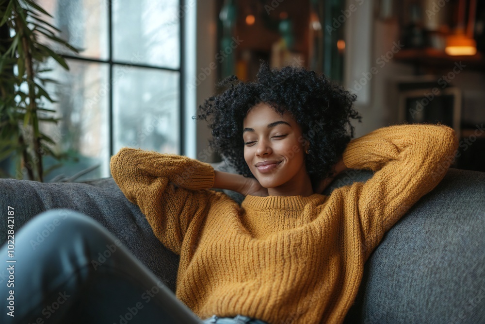 Obraz premium Happy african american woman relaxing sitting in a comfortable sofa at home