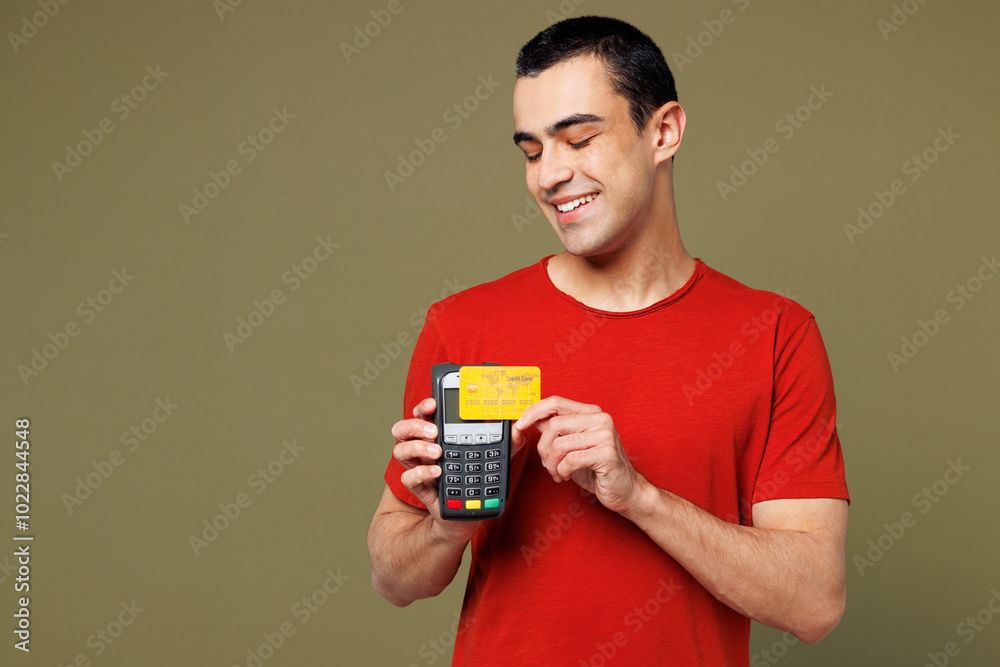Young middle eastern man wear red t-shirt casual clothes hold wireless modern bank payment terminal to process acquire credit card isolated on plain pastel green background studio. Lifestyle concept. Young middle eastern man wear red t-shirt casual clothes hold wireless modern bank payment terminal to process acquire credit card isolated on plain pastel green background studio. Lifestyle concept.